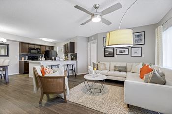 A living room hardwood-style flooring and a ceiling fan